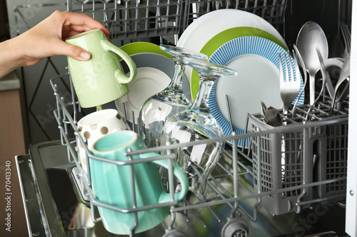 Open dishwasher with clean utensils in it photo