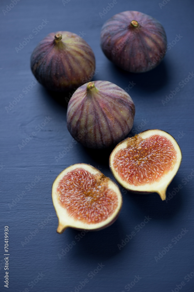 Whole and sliced fig fruits, dark blue wooden background Whole and sliced fig fruits, dark blue wooden background