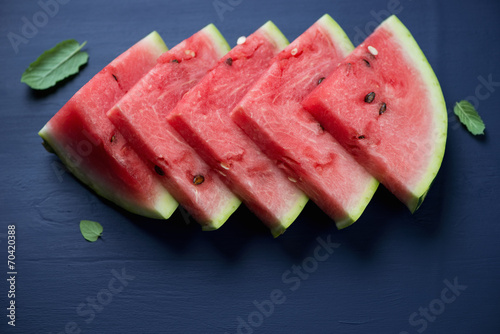 Watermelon slices over dark blue wooden surface, high angle view