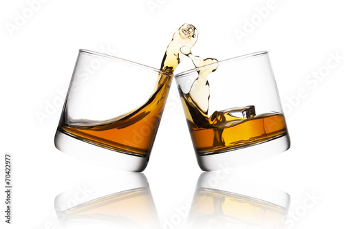 Splash of whisky in two glasses isolated on white background