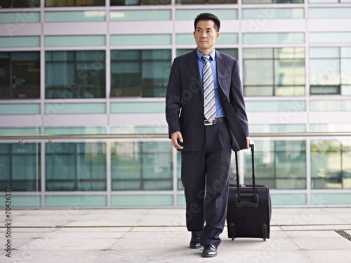 asian business traveler walking with luggage