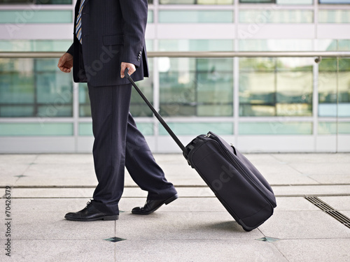 asian business traveler walking with suitcase