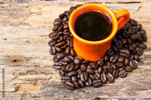 Cup of black coffee and Coffee beans arranged in heart shape on