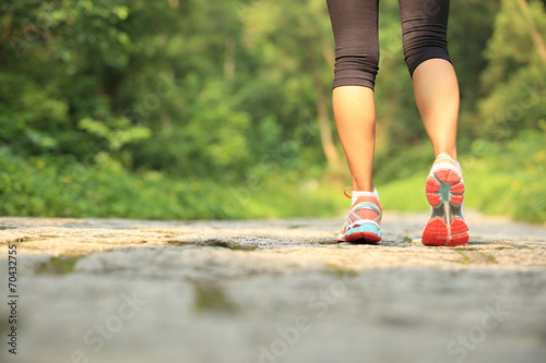 young fitness woman legs walking on forest trail 