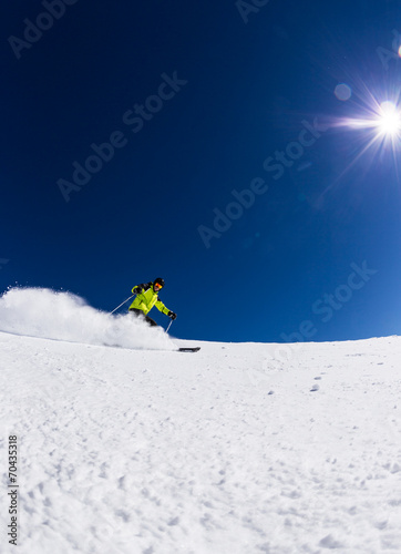 Alpine skier on piste, skiing downhill