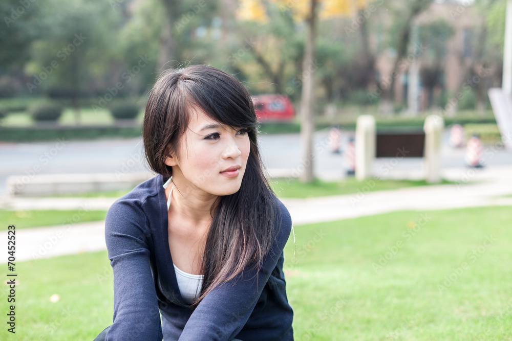 young asian woman sits on the grass field young asian woman sits on the grass field