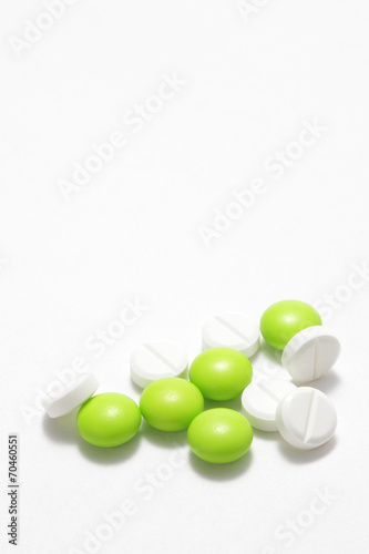 Green and white pills on white background © haru