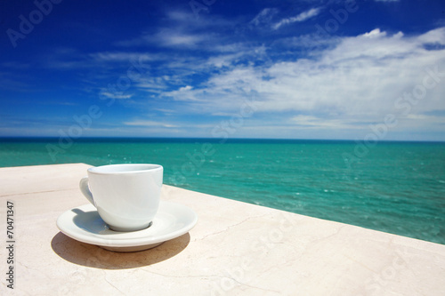 A cup of coffee on table with sea at the background
