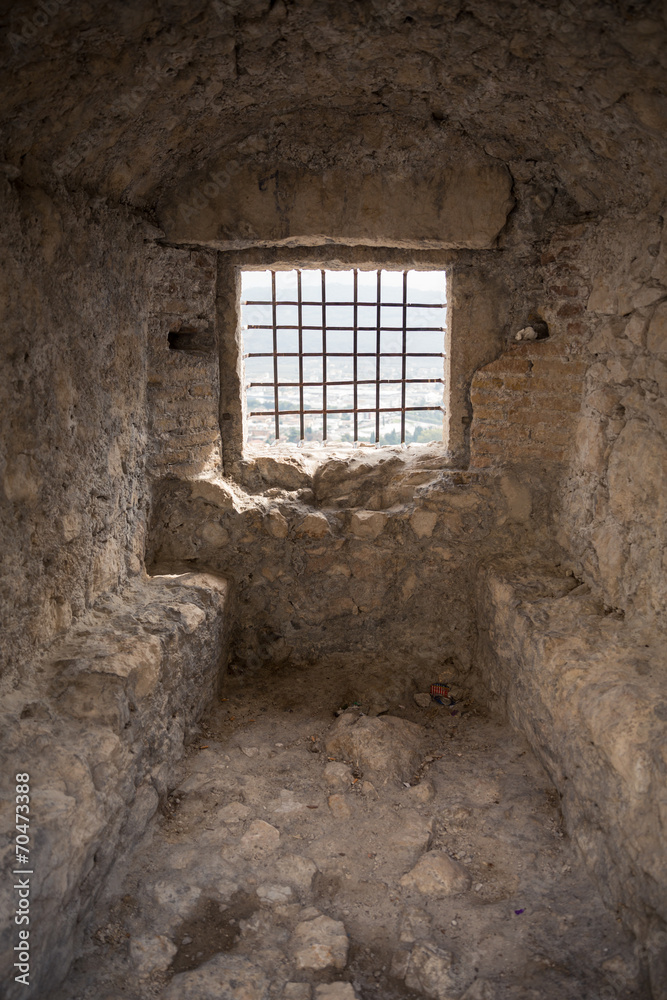 medieval prison room with metal grid in window
