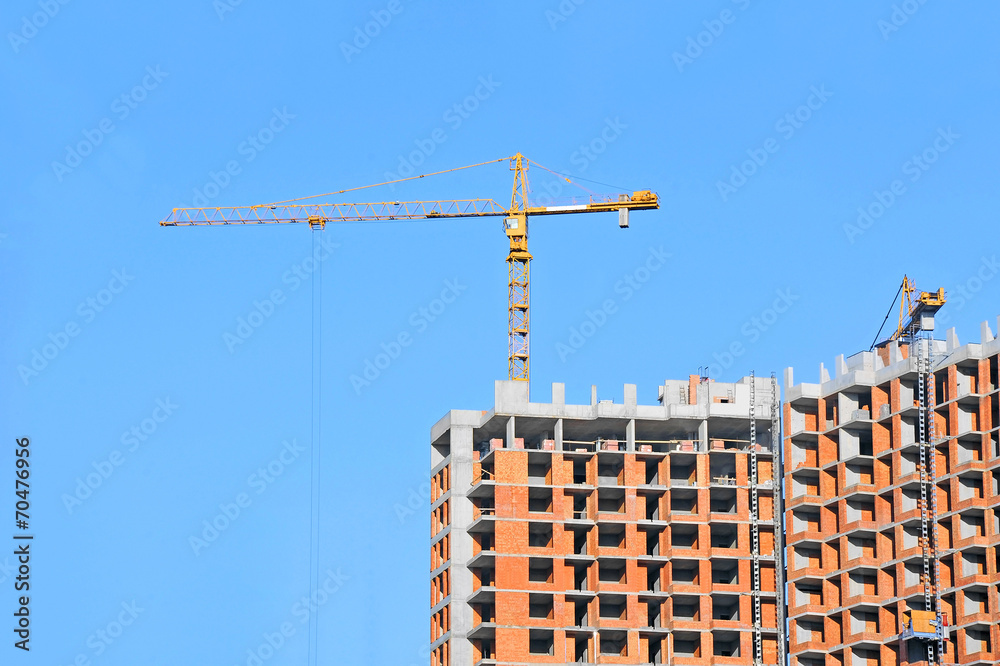 Fototapeta premium Crane and building construction site against blue sky