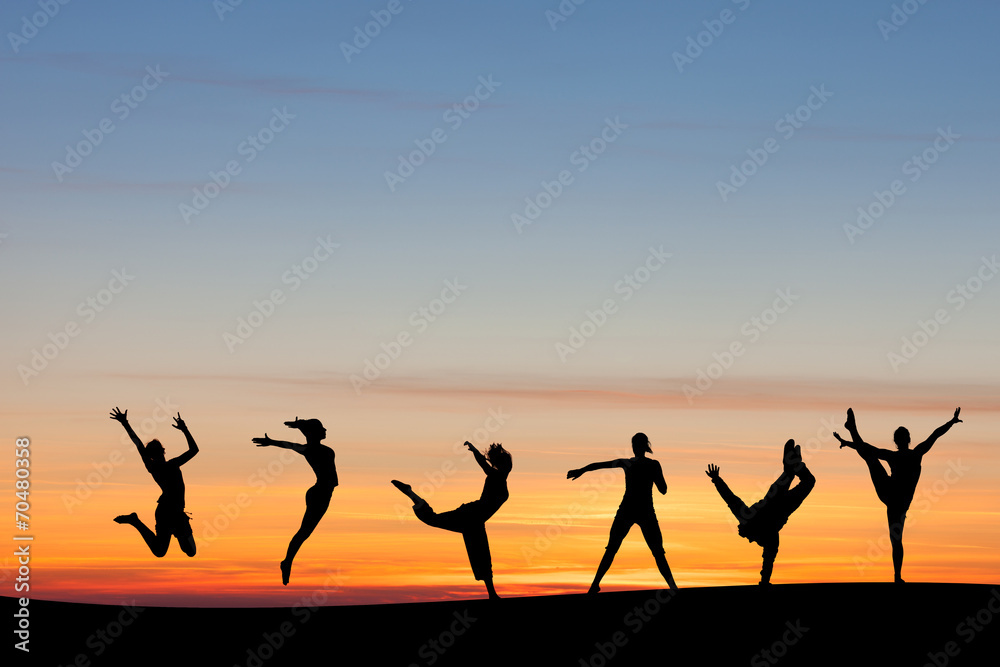 silhouetted group tumbling and dancing in sunset