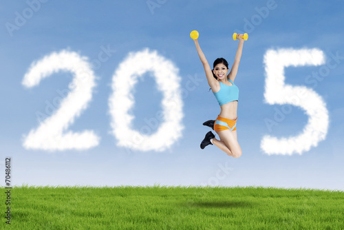 Asian woman with dumbbells in field