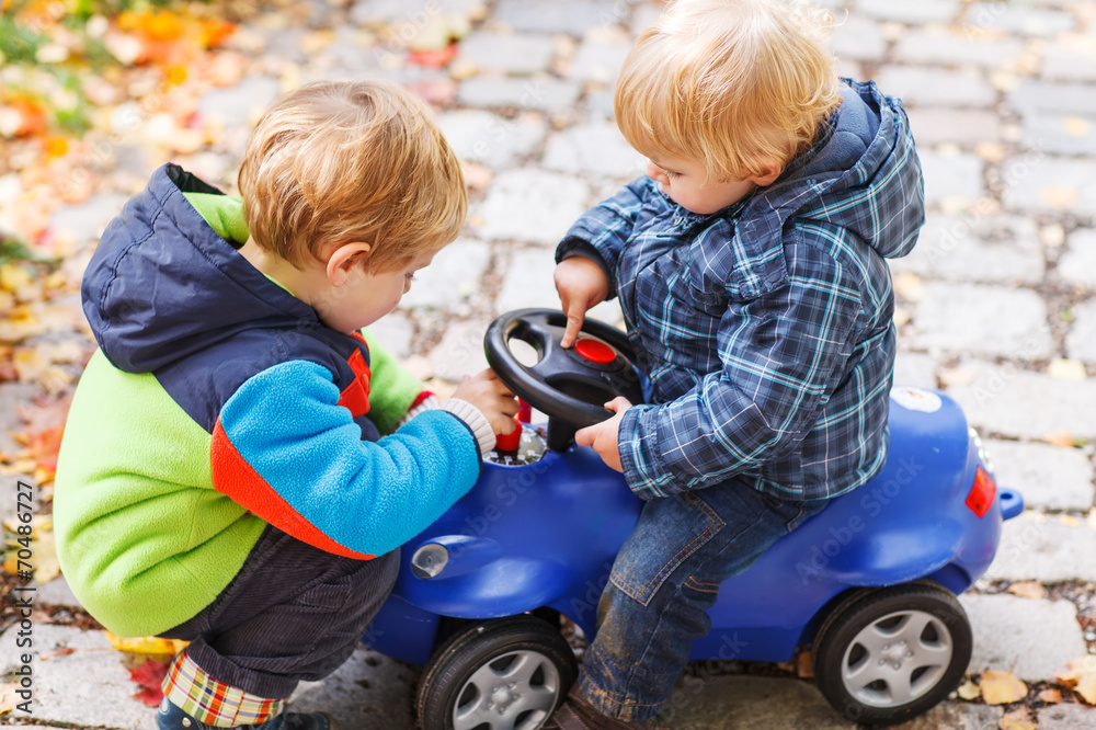 Two little sibling children playing with toy car on autumn day. Two little sibling children playing with toy car on autumn day.