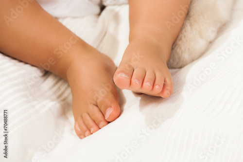 Gambe di un neonato sdraiato su un lenzuolo bianco