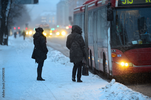 Commuters waiting for arriving bus in snowstorm photo