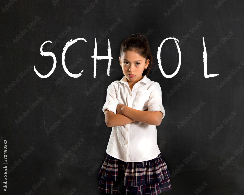 hispanic moody little schoolgirl in uniform standing upset