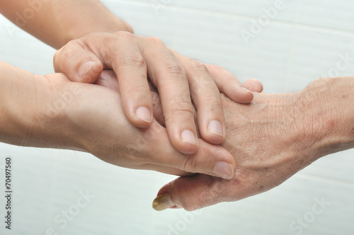 Young male hand holding an old woman's hand