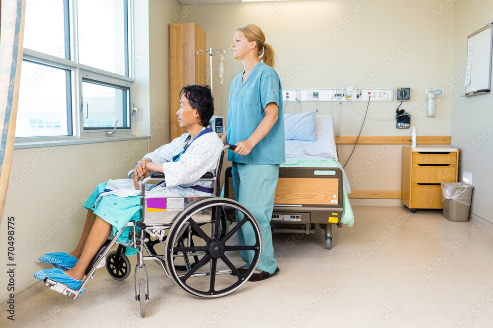 Nurse With Patient Sitting On Wheel Chair At Hospital Window