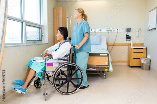 Nurse With Patient Sitting On Wheel Chair At Hospital Window