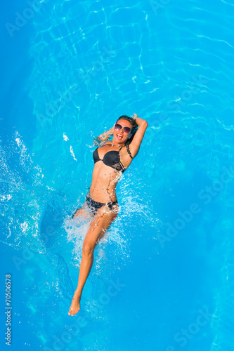 Beautiful young girl floating in pool on her back