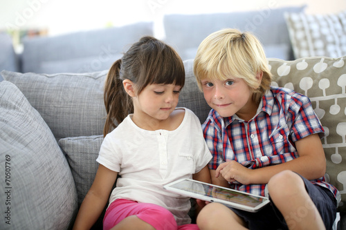 Kids sitting in sofa and playing with tablet