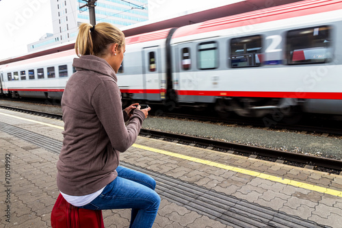 Frau wartet auf Zug und schreibt SMS photo