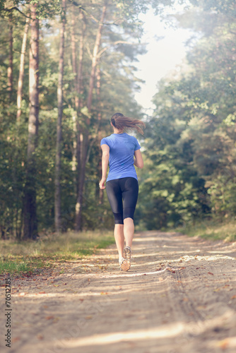 Athletische junge Frau läuft im Wald, Blick von hinten