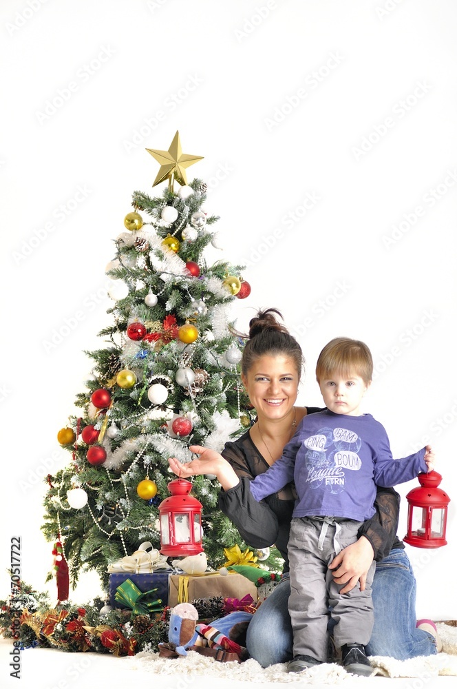 Mother and their small child sits near Christmas tree with lamps Mother and their small child sits near Christmas tree with lamps
