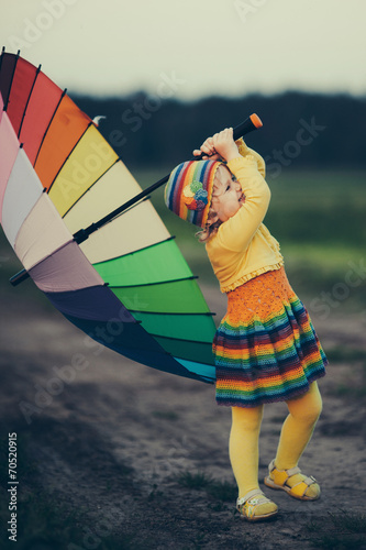 little girl with rainbow umrella in the field photo