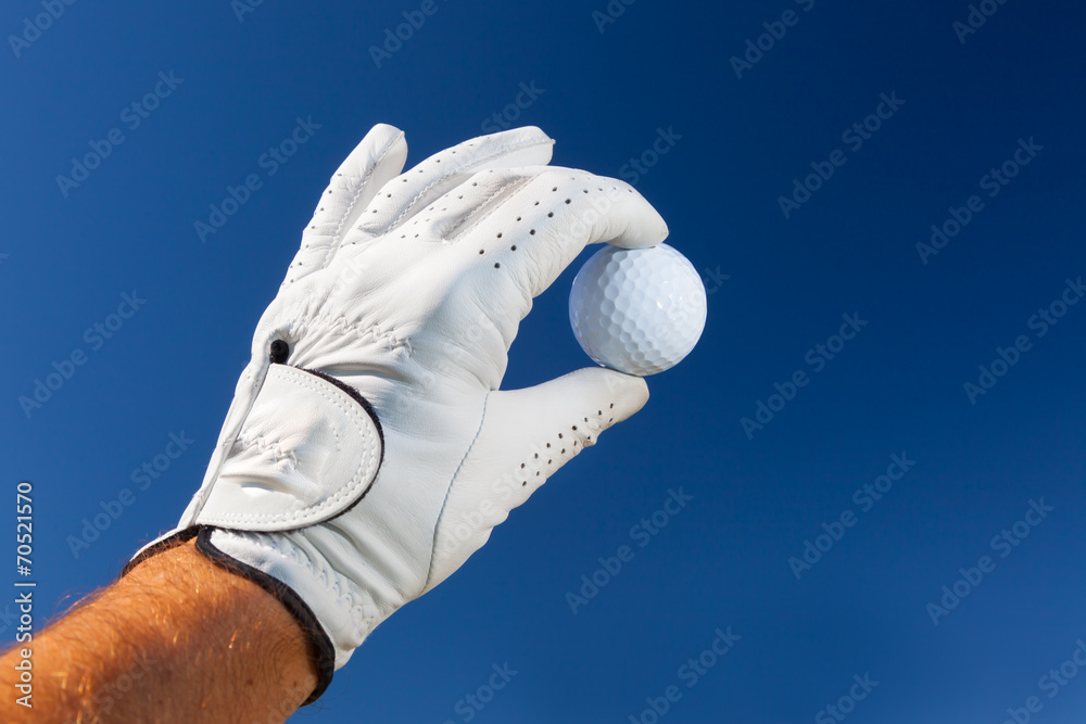 Hand wearing golf glove holding a white golf ball - obrazy, fototapety, plakaty 