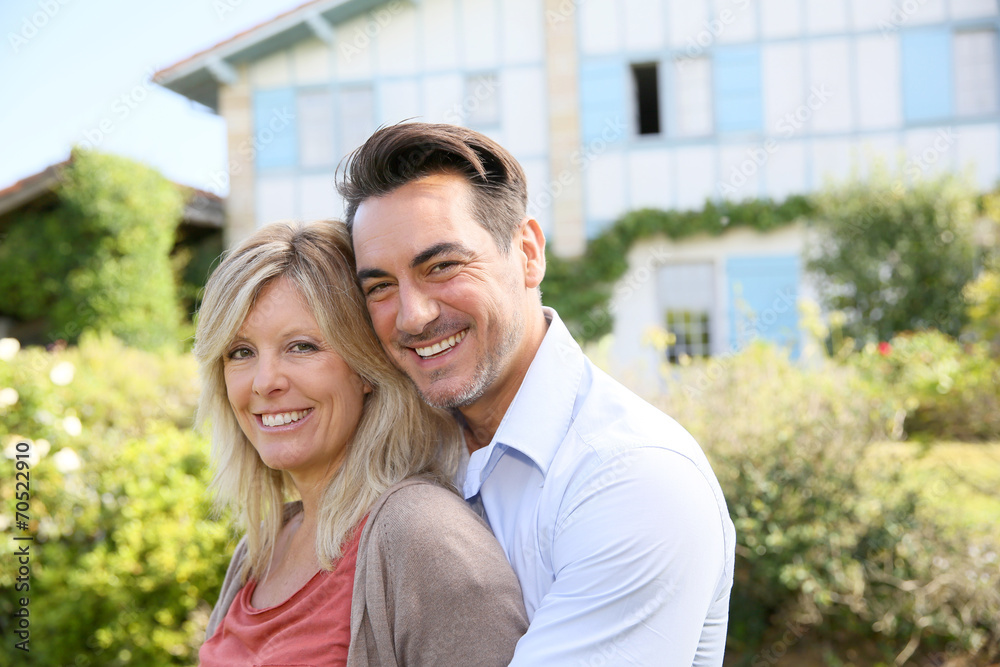 Cheerful mature couple standing in front of house Cheerful mature couple standing in front of house