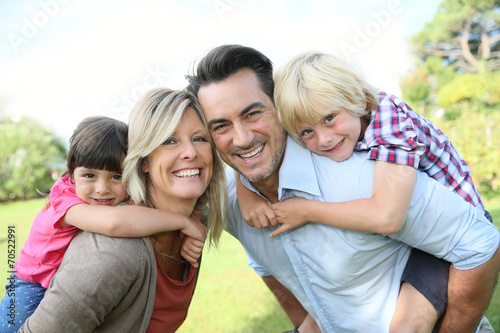 Parents giving piggyback ride to kids in park