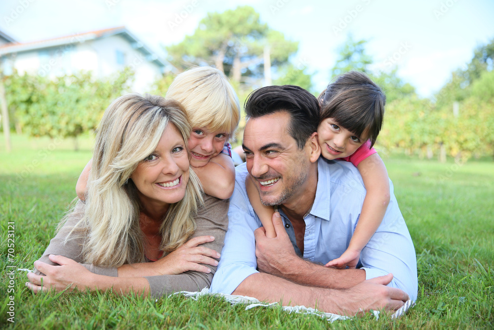Family of four laying on grass in front of house Family of four laying on grass in front of house