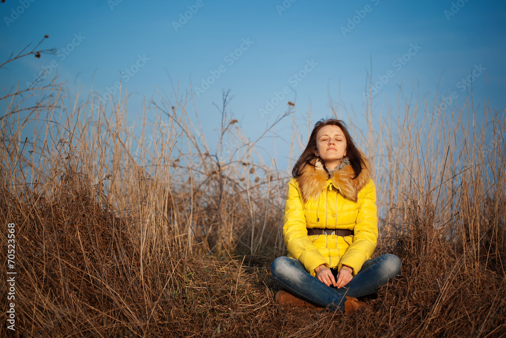 youn girl sitting on yellow autumn grass