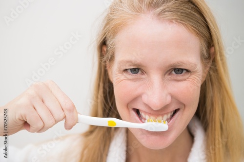Happy blonde brushing her teeth