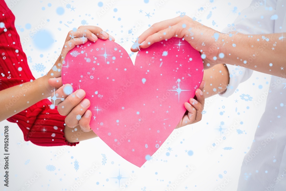 Composite image of couples hands holding pink heart Composite image of couples hands holding pink heart