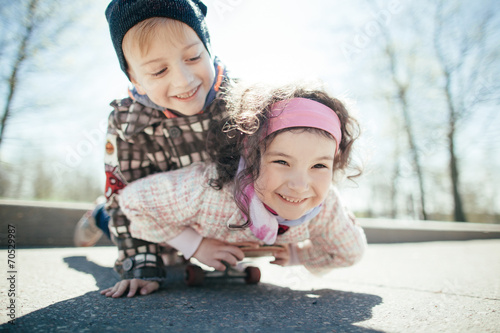 little boy and girl skaiting on the street photo