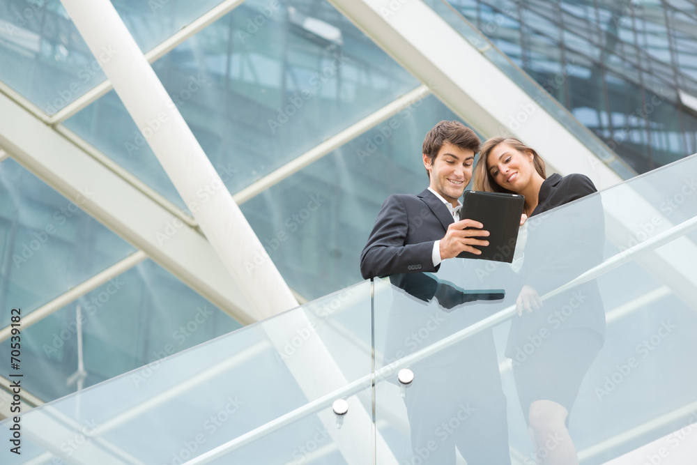 Young business couple with modern building behind with tablet Young business couple with modern building behind with tablet