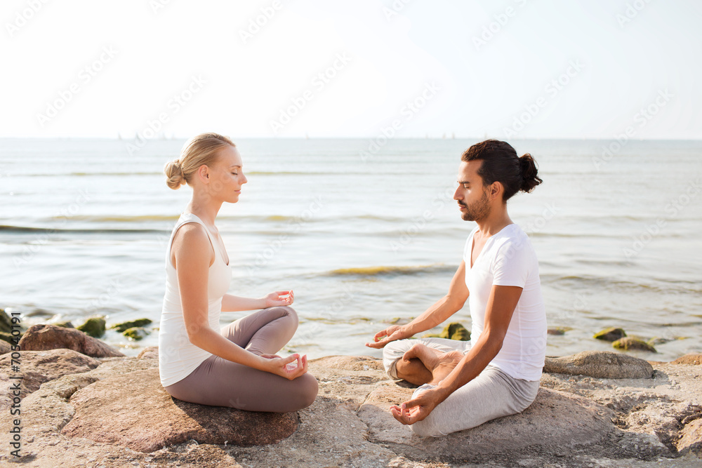 Fototapeta premium smiling couple making yoga exercises outdoors