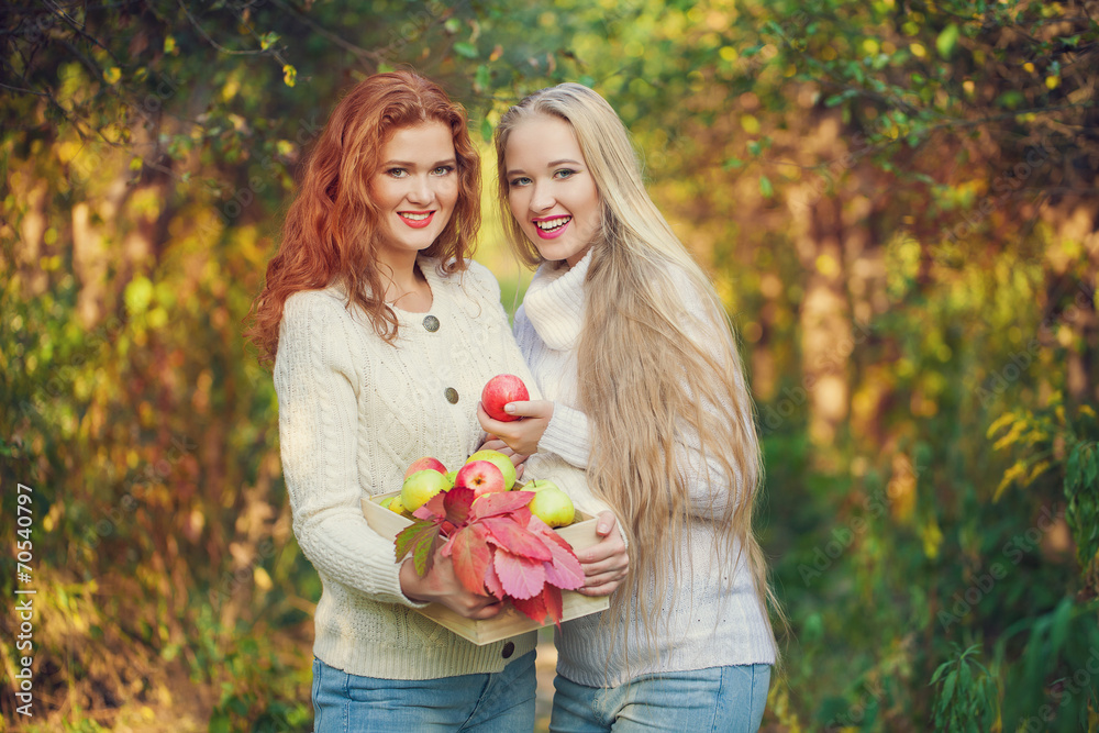 Fototapeta premium Two sisters in Fall yellow apple orchard. Autumn outside in colo