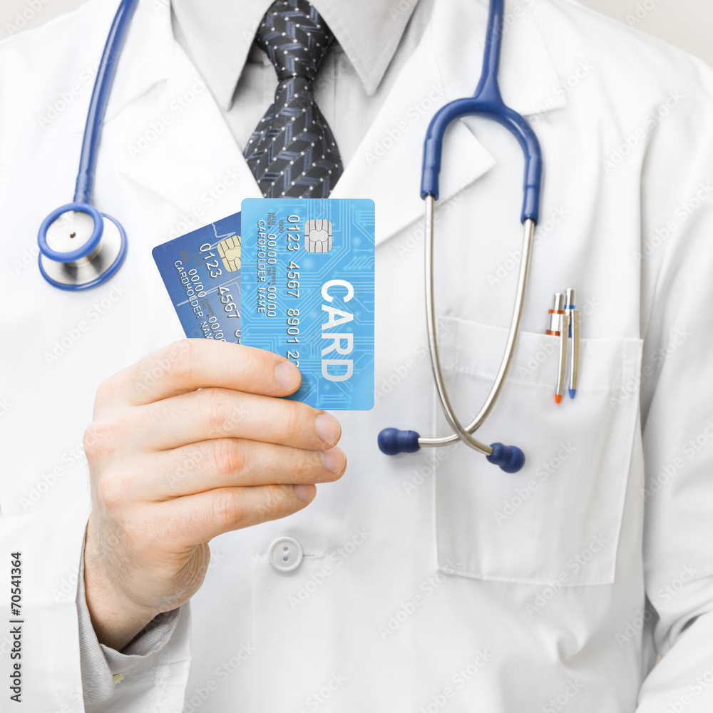 Medocal doctor holding credit cards in his hand - 1 to 1 ratio Medocal doctor holding credit cards in his hand - 1 to 1 ratio