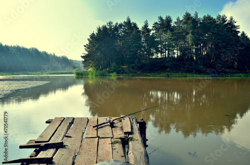 wooden bridge on the lake with a fishing rod