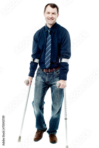 Foto Man walking with crutches isolated on white