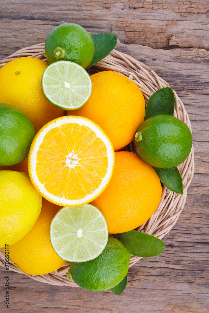 Mix of fresh citrus fruits in basket on wood Mix of fresh citrus fruits in basket on wood