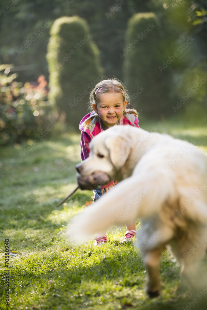 Junges Mädchen spielt mit Golden Retriever im Garten Junges Mädchen spielt mit Golden Retriever im Garten