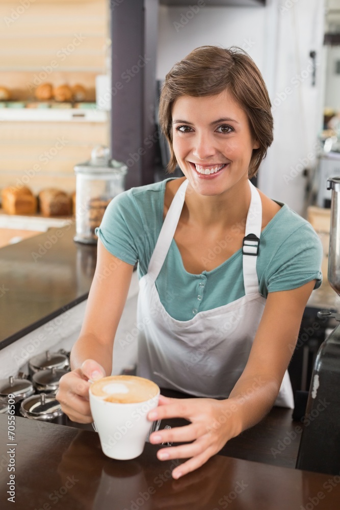 Pretty barista offering cup of coffee smiling at camera Pretty barista offering cup of coffee smiling at camera