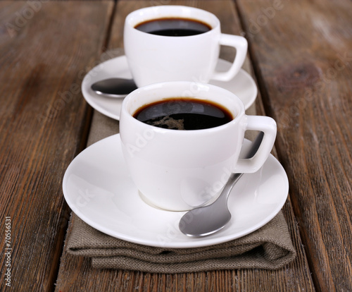 Two cups of coffee on sackcloth napkin on wooden background