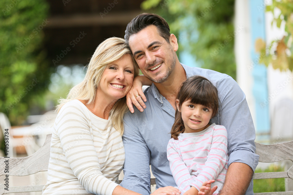 Portrait of parents with daughter sitting in front of house Portrait of parents with daughter sitting in front of house