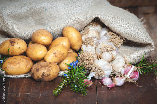 Potatoes and garlic in canvas sack on rustic wooden table