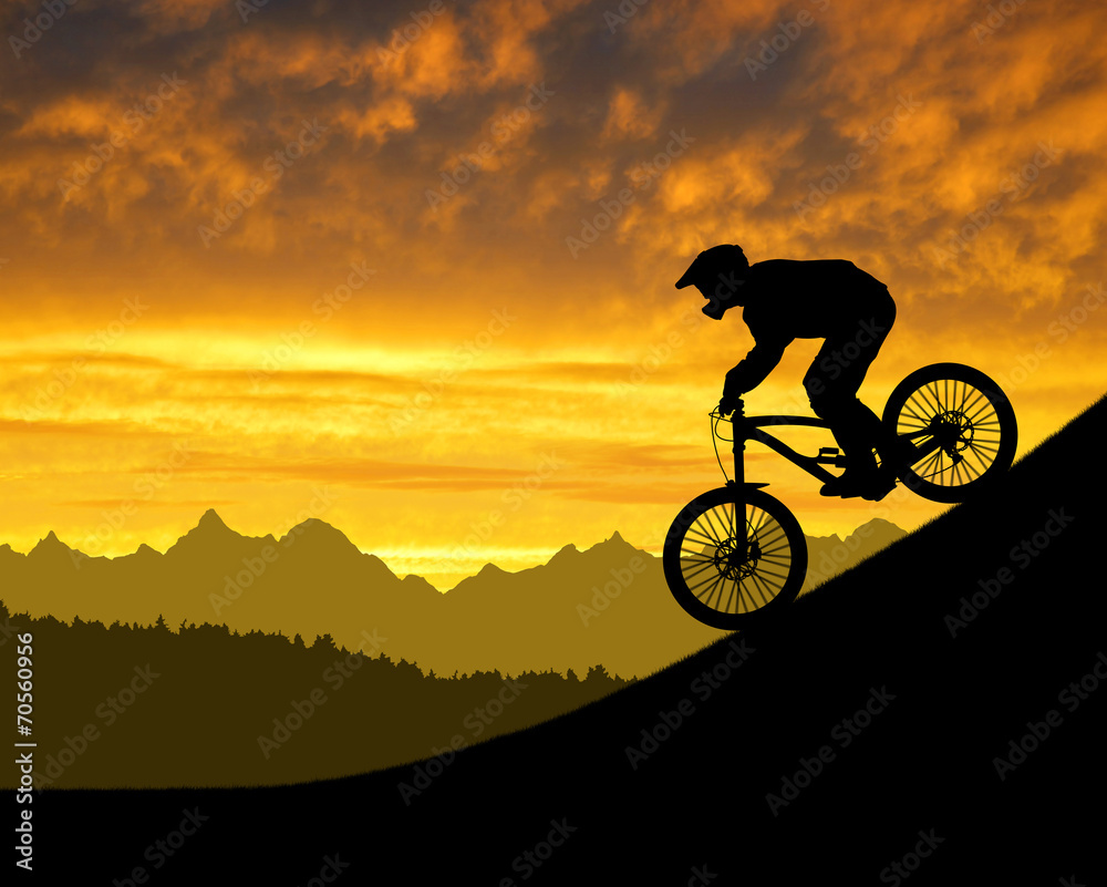 Fototapeta premium silhouette of the cyclist on downhill bike at sunset